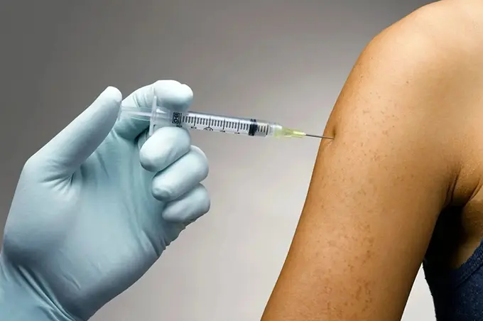 A person is getting an injection in his arm.